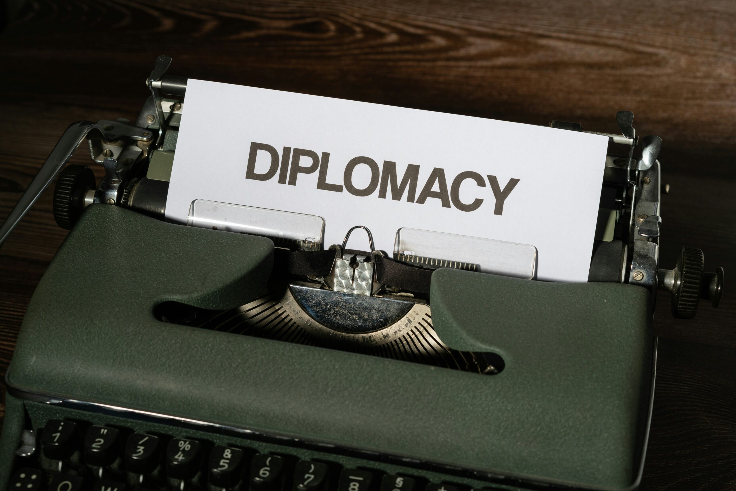 A close up of a typewriter with a piece of paper with the words "DIPLOMACY" coming out of it.